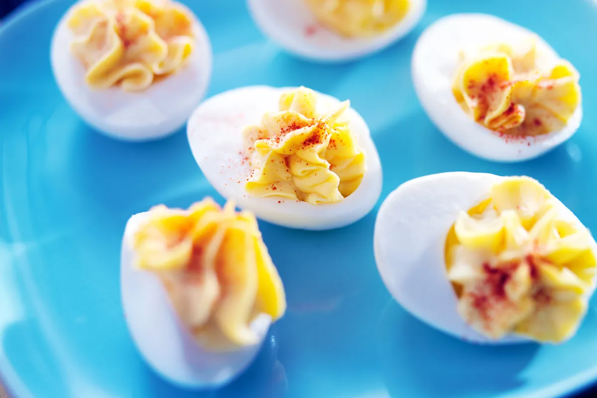 A blue plate containing deviled eggs with a yellow filling. 